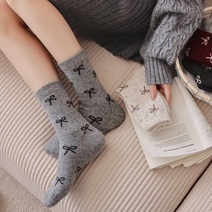 Close-up of thick wool socks featuring black bow patterns and colorful speckled knit texture