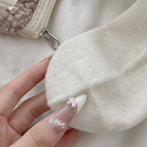 Close-up of white knit calf socks and brown fuzzy plush pouch with metal zipper detail