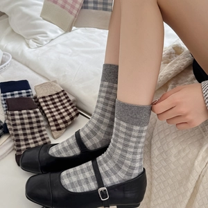 Detail of plaid crew socks in grey and white paired with black Mary Jane shoes