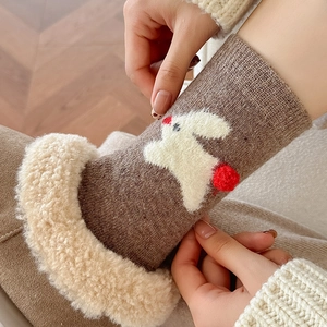 Close-up of fluffy white faux fur cuff and cute bunny embroidery on brown winter socks