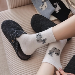Close-up of cat pattern socks with plaid bow detail and felt slippers in cozy home setting