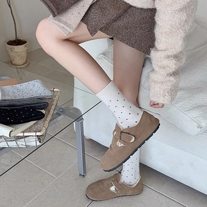 Detail of brown suede mule shoes paired with white polka dot knit mid-calf socks