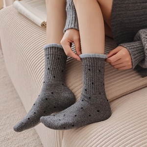 Macro shot of thick wool socks with polka dots and blue contrast trim on cozy background