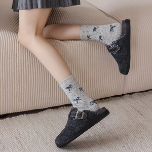 Detail of dark grey wool felt clogs with metal buckle and blue bow knit socks
