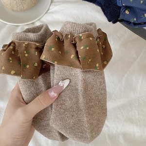 Detaillierte Strickstruktur beiger Wollsocken mit dunkelbraunen Rüschen und Blumen