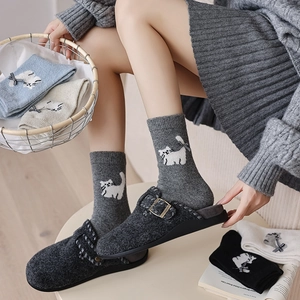 Detail shot of knitted socks with cat embroidery and black bows in a cozy home setting