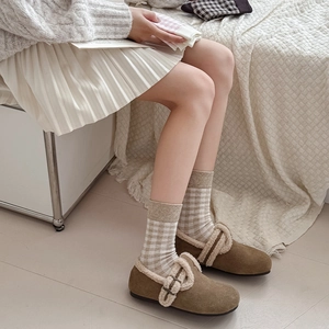 Detailed view of brown suede loafers with white shearling trim and plaid socks