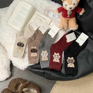 Detail of five pairs of thick wool socks with cute cartoon bear embroidery in autumn colors