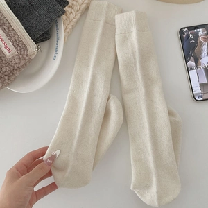 Detailed close-up of ribbed texture on cream-colored warm mid-calf knit socks