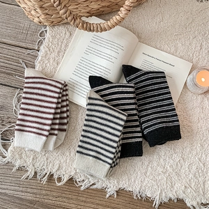 Detailed close-up of striped wool socks with elastic ribbed cuffs on a white rug