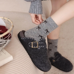 Detailed texture of dark grey felt clogs with metal buckle and bow print wool socks