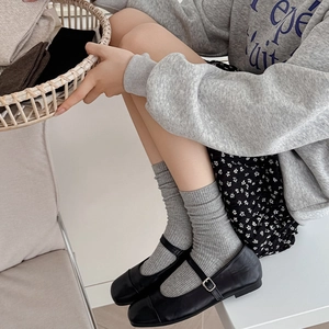 Gray vertical striped slouch socks paired with black Mary Jane shoes for casual style