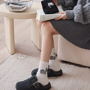 Detail of white knit socks with cat embroidery, bow detail, and gray felt mules