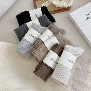 Close-up of thick ribbed wool socks in six earth tones with minimalist paper packaging