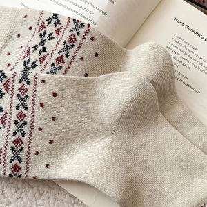 Dettaglio della trama a maglia di calze di lana con motivi Fair Isle su un libro