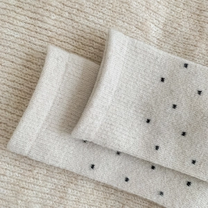 Close-up of beige wool blend socks with black polka dots and soft knit texture