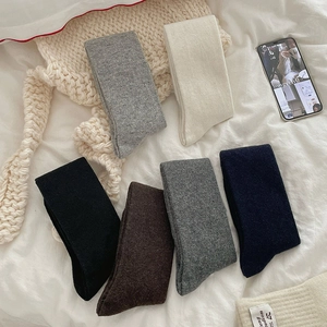 Close-up of thick knitted winter calf socks in six colors on a white bedding background