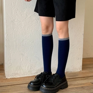 Detail of navy blue knee-high socks with grey ribbed cuffs and wool texture finish