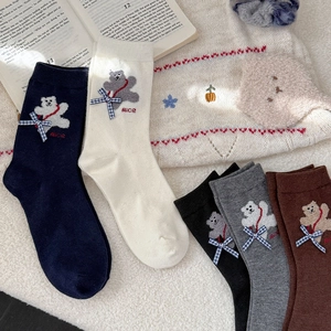 Close-up of thick winter socks featuring embroidered bear, bow and Nice lettering details