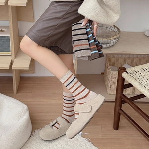 Pink and grey striped mid-calf socks styled with vintage shoes in a warm home setting
