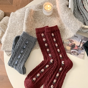 Detailed close-up of wool knit crew socks featuring floral embroidery and cable texture