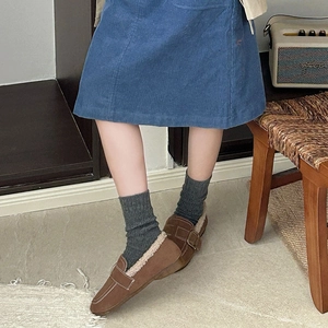 Close-up of brown suede loafers with warm faux shearling lining and metal buckle detail