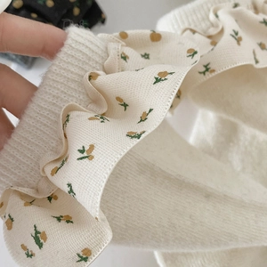 Nahaufnahme der cremefarbenen Strickstrümpfe mit Spitzenrand und Blumenstickerei