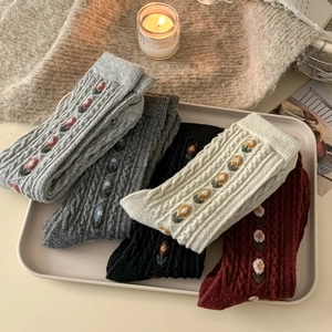 Detail of floral embroidery and cable knit texture on cozy wool crew socks in five colors