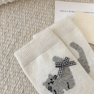 Close-up of knit wool cat socks with plaid bow detail and soft texture pattern