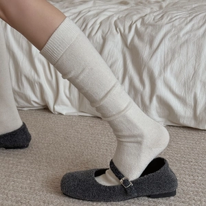 Close-up of cream white knitted slouch socks paired with grey Mary Jane shoes