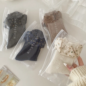 Detail von vier Paar Wollsocken mit Spitzenbesatz in minimalistischen Reißverschlussbeuteln