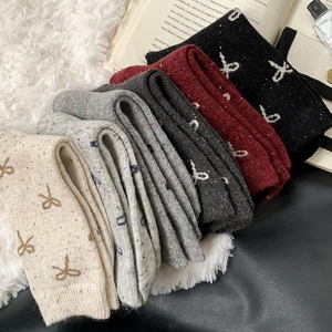 Close-up of five colorful knitted wool socks featuring delicate bow jacquard patterns