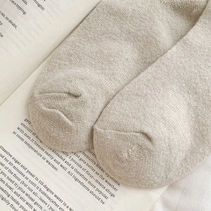 Detail shot of oatmeal beige knitted wool socks on a book showing the fine texture
