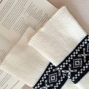 Close-up of Fair Isle knit leg warmers showing intricate white wool texture and patterns