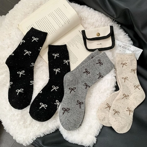 Detail of wool blend socks featuring bow tie patterns and soft knit texture in warm lighting
