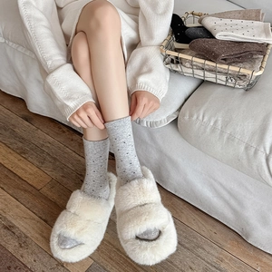 Close-up of off-white faux fur cross strap platform slippers with warm socks