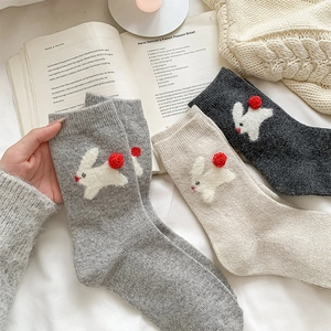 Close-up of thick knit wool socks with cute 3D bunny and red pom-pom details