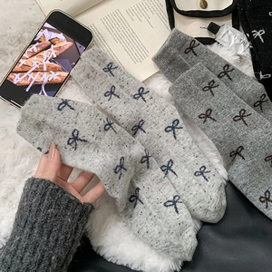 Detailed close-up of grey wool knit socks with bow embroidery in a cozy lifestyle setting