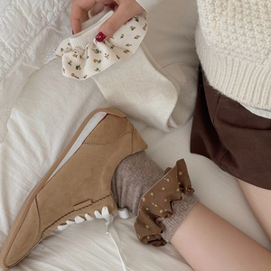 Nahaufnahme der floralen Rüschenbündchen an gemütlichen Wollsocken in Creme und Braun
