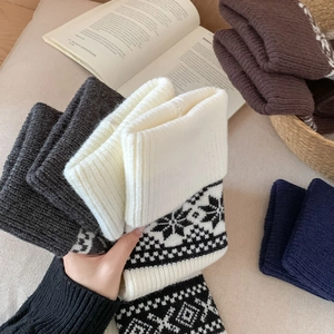 Close-up of Nordic Fair Isle knitted leg warmers with snowflake patterns in cozy winter setting