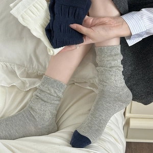 Detailed view of grey and navy blue color-blocking knit cotton crew socks in a cozy setting