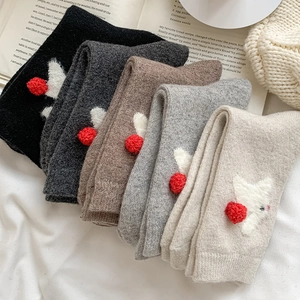 Detail of wool socks featuring 3D white bunny embroidery and red pom-poms in five colors
