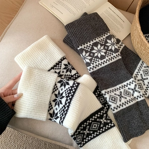 Close-up of Fair Isle knit leg warmers with Nordic snowflake patterns in white and grey