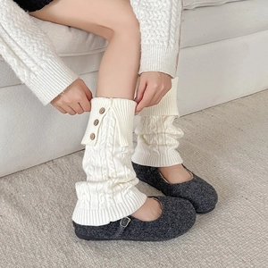 Detail of white cable knit leg warmer with vintage buttons and textured stitch pattern