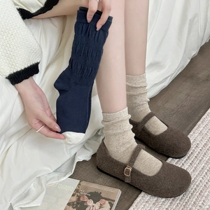 Close-up of beige and navy ribbed knit slouch socks with brown Mary Jane shoes