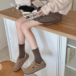 Close-up of wool socks with polka dots paired with suede clogs featuring cozy fur lining