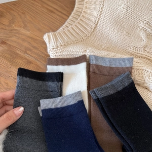Detail of wool blend calf socks in various colors with ribbed cuffs on wooden table