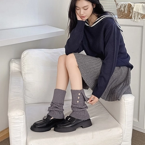 Detail of dark grey cable-knit leg warmers with three decorative wooden side buttons