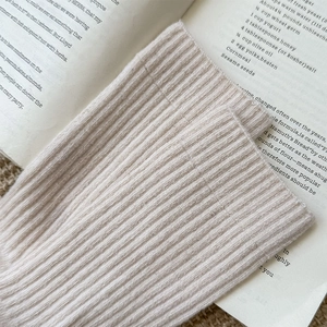 Detailed knit texture of cream wool socks placed on a vintage book for a cozy autumn look