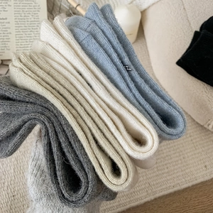Detail of wool-knit crew socks in grey, cream, and blue with thick ribbed texture